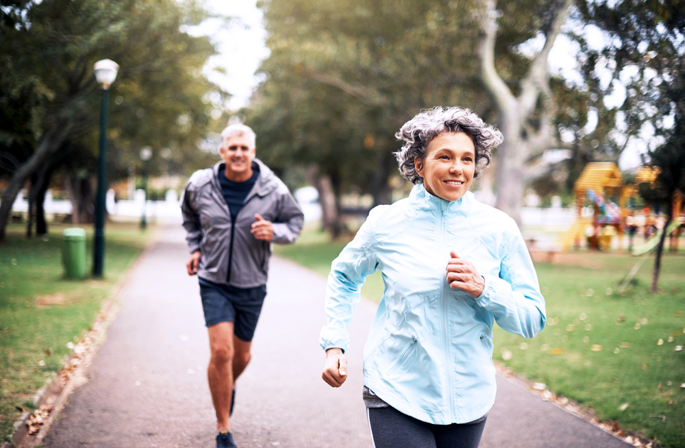 Two people jogging in a park after effectively managing their sports injuries